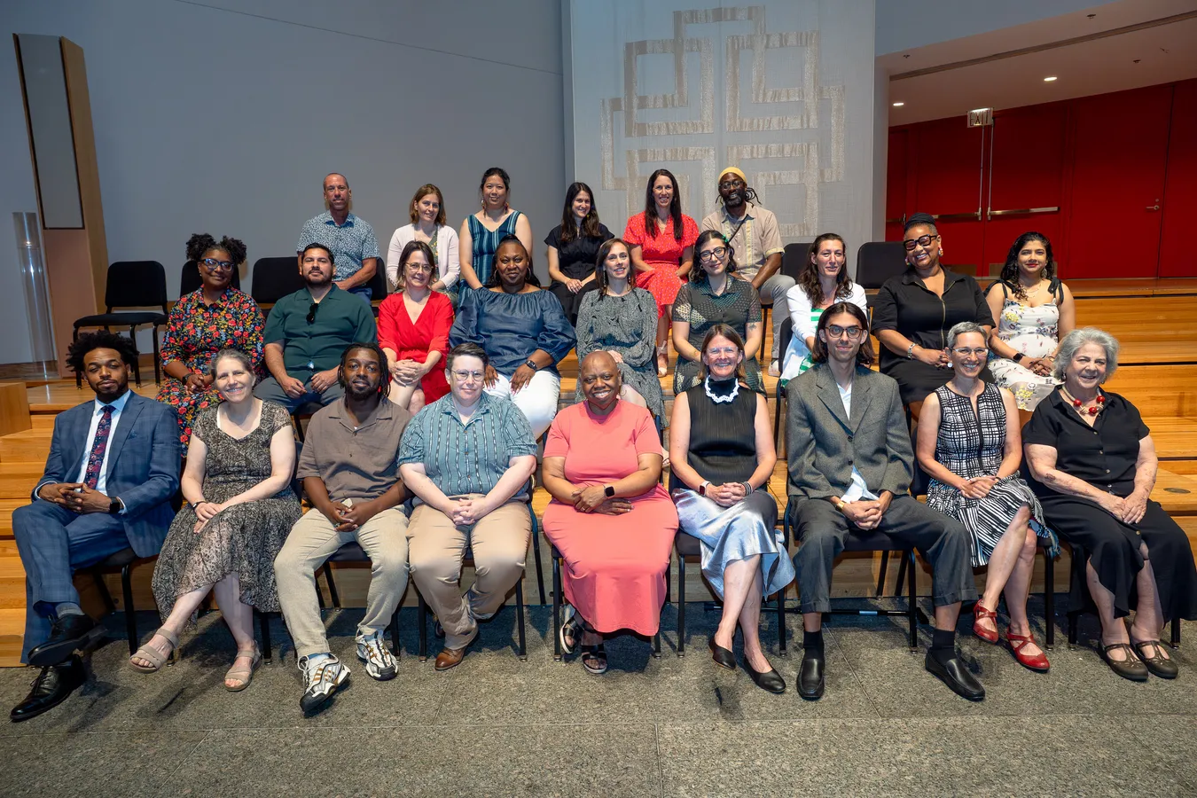 The Urban Academy staff seated in rows for a group portrait on the auditorium steps at graduation
