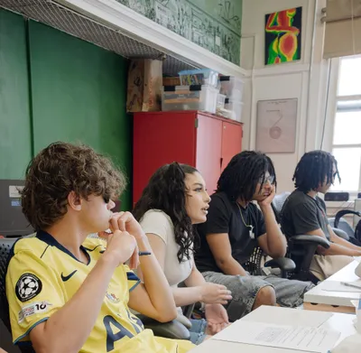 Four students of different ages sitting in a row, listening intently during a class discussion